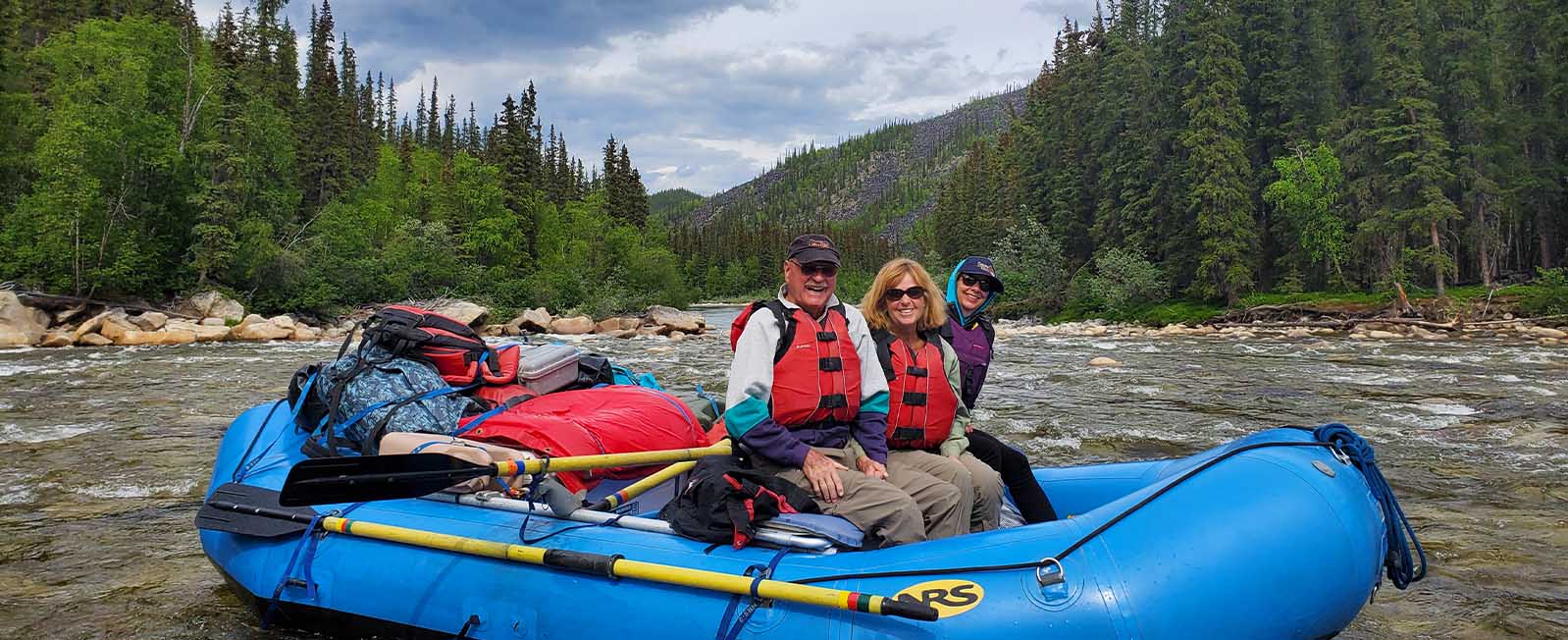 Three rafters in a boat on the Charley River in Alaska