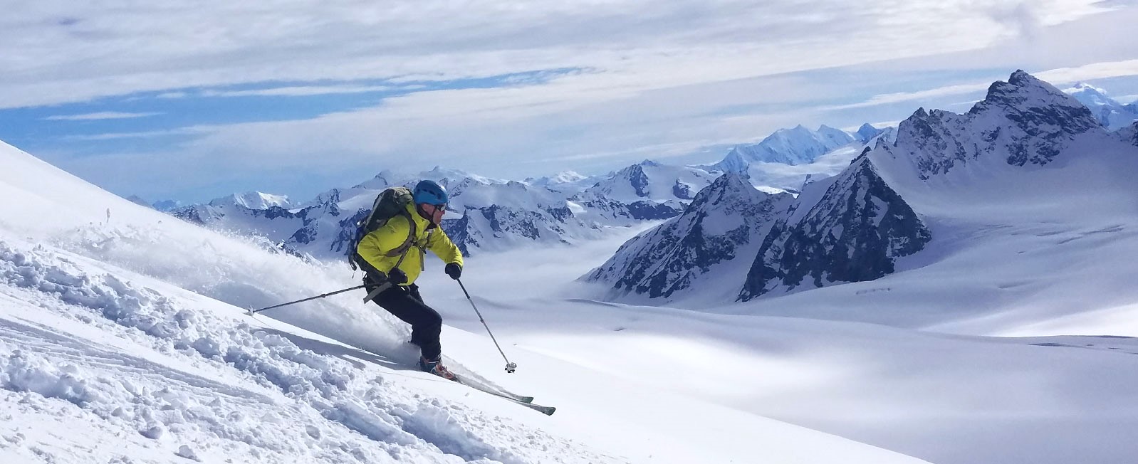Man in yellow jacket skis the Alaskan backcountry
