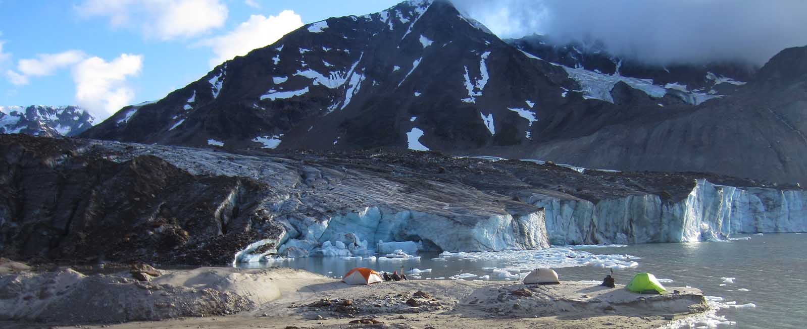 Tents set up in front of blue calving glacier