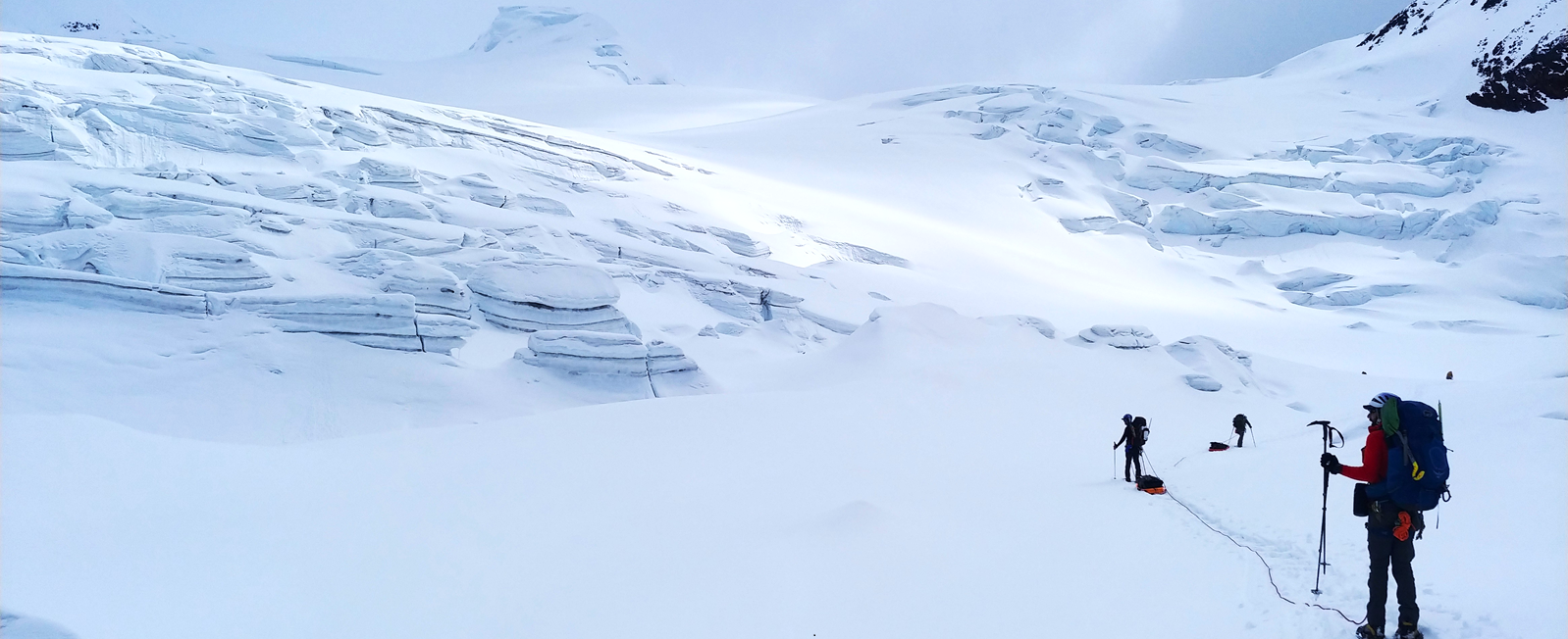 Mountaineers approaching a snow-covered ice fall on Mt. Sanford