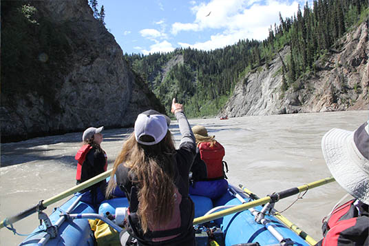 A raft guides points out a beautiful feature of the river to his clients on the Nizina River