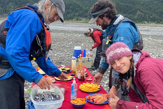 Enthusiastic rafters huddle over a spread of fresh food