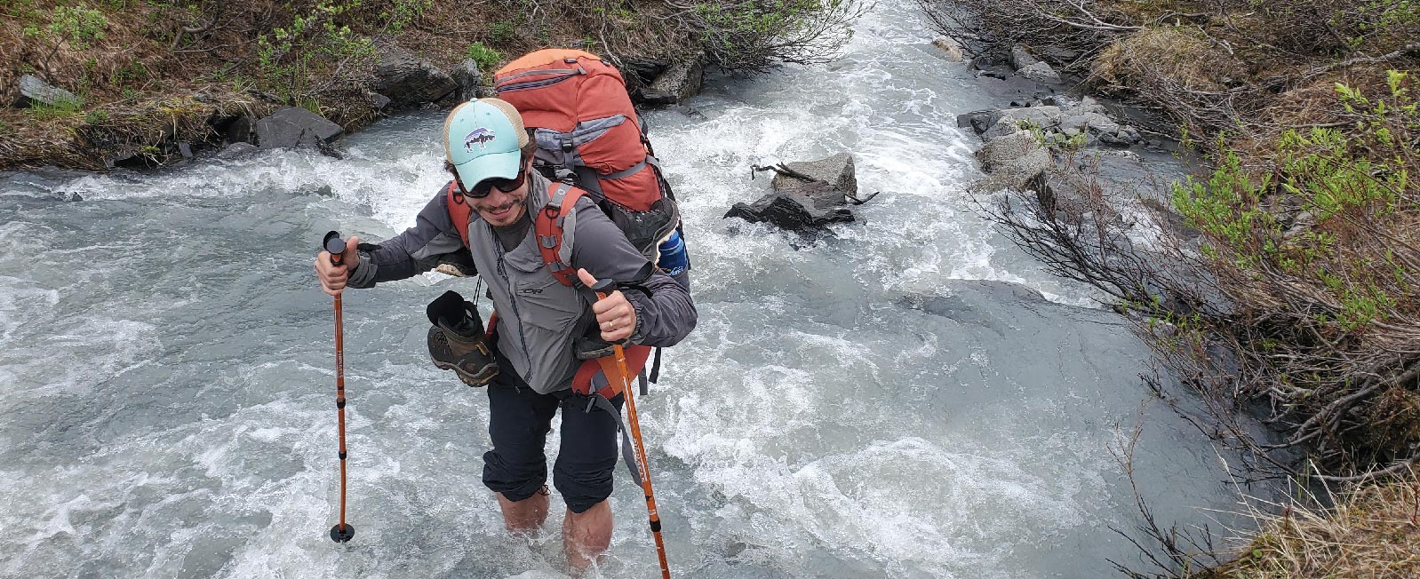 Backpackers crossing a creek with trekking poles