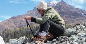 Woman in a beanie straps on crampons for a Glacier Hike in Alaska