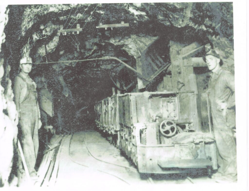 Historic photograph inside a mine with a miner and train cart
