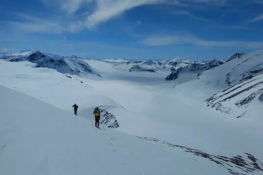 Two skiers work their way up a slope in the backcountry