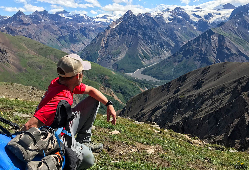 Hiker sits atop a mountain looking down into valley below