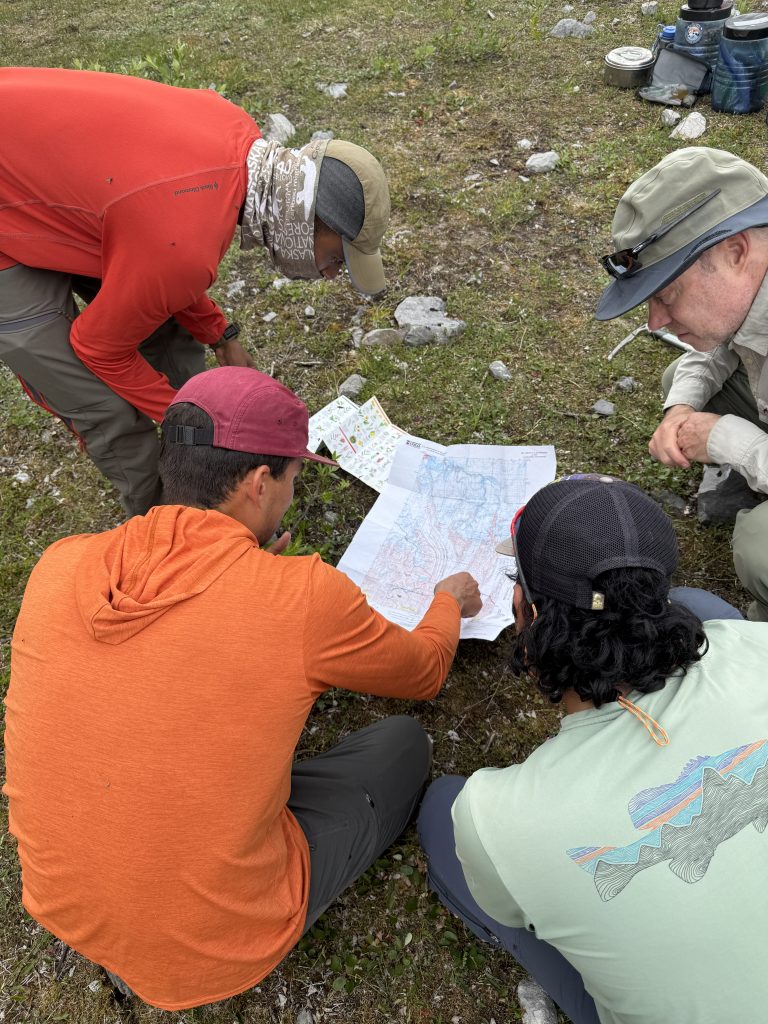 People huddled around map in the backcountry