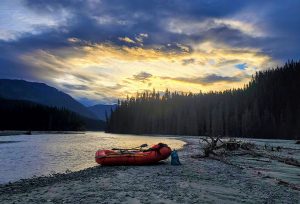 Red raft on shore of an Alaskan river at sunset