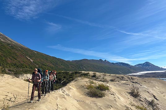 Backpackers lined up on a sandy ridge
