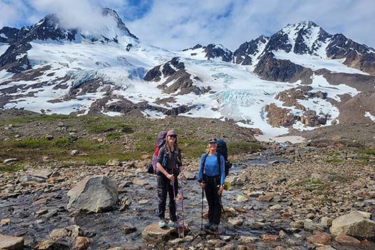 Two happy backpackers post in from of a glaciated mountain