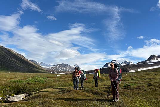 Backpackers walking through a valley in Alaska