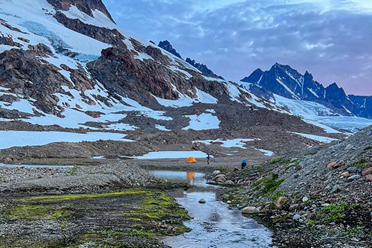 A couple of tents are dwarfed by huge glaciated peaks