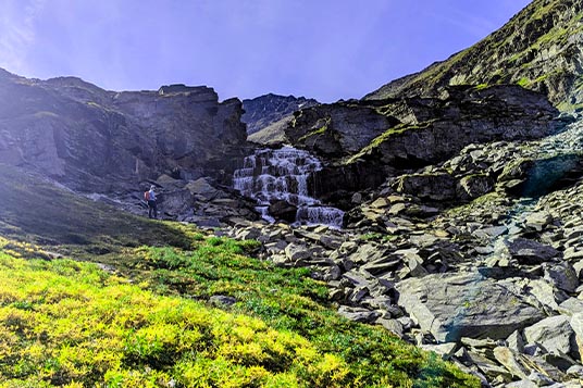 A hiker near a waterfall in Alaska