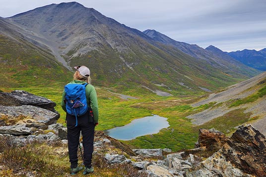 A female hiker looking across an alpine valley with a blue lake