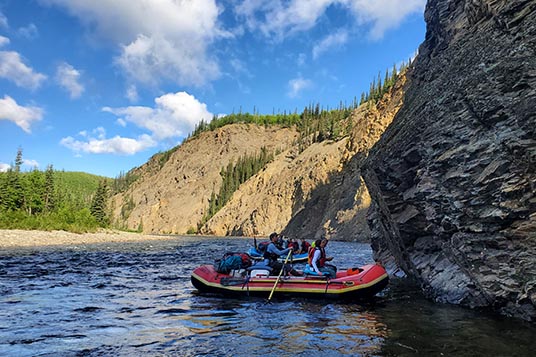 Two rafts nearly touch a cliff as they float the Charley River in Alaska