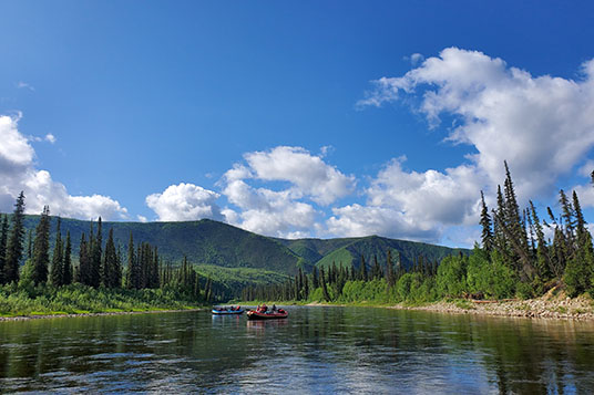 Two rafts float down a peaceful and clear river in Alaska