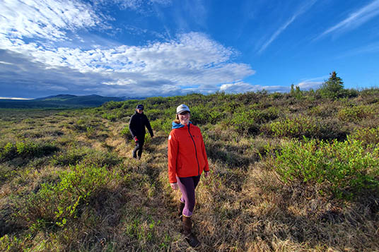 Two smiling women walking on a trail in Alaska