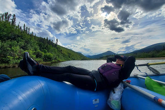 A woman laying on a raft floating down the river