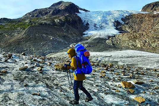 A backpacker traverses a glacier in the Alaskan mountains