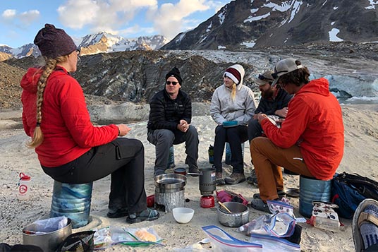 A group of trekkers sits in a circle for lunch in the backcountry