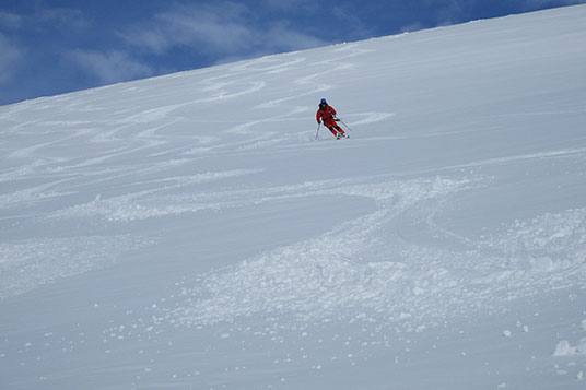A skier carving up turns on a wide open slope