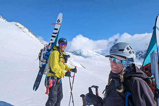 Two backcountry skiers smile at the camera