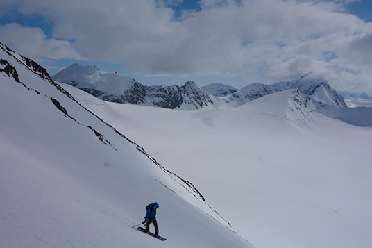 A person on a snowboard descending a steep slope