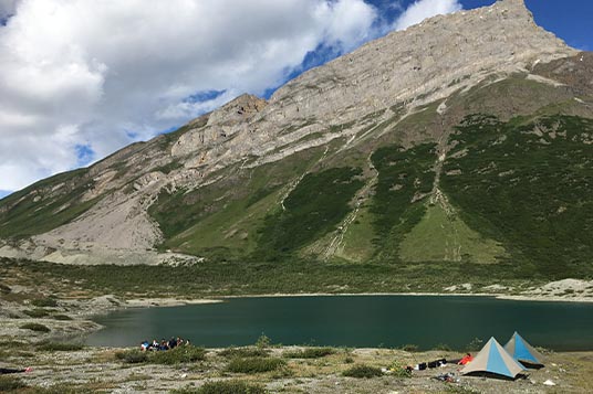 A group camped out by a turquoise lake near Mount Donoho
