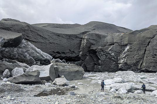 Calving ice cave with small people in front presenting an impressive sense of scale