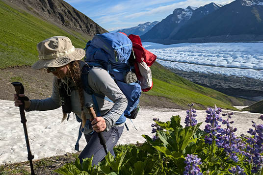 Hiker climbing a slope with Alaskan glaciers below