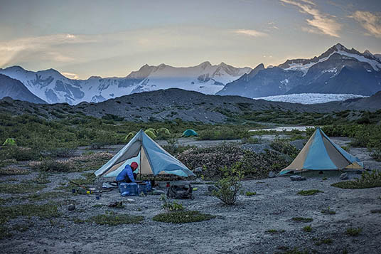 Two tents and a guide in the evening light of the Wrangells backcountry