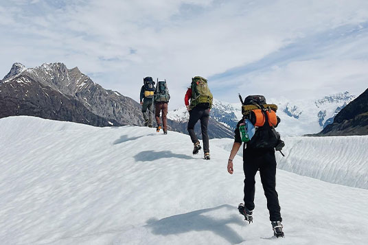 Backpackers hike up the Root Glacier in crampons
