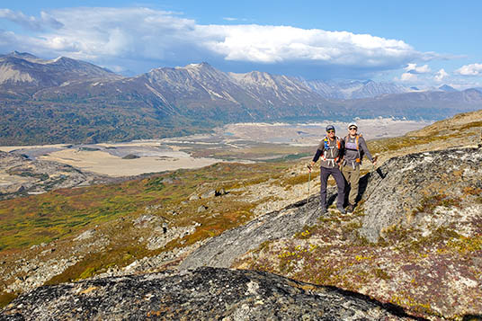 Two hikers pose in front of a valley in Wrangell - St. Elias National Park