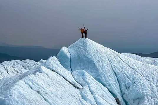 Two hikers on a steep icy hill on a glacier