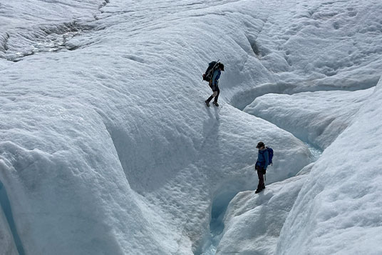 Two hikers on the slopes of the Root Glacier