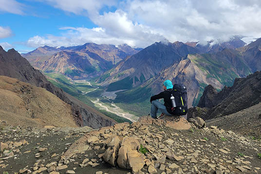 A backpacker admires the view over the Chitistone River