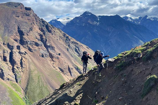 Two backpackers work through a challenging, rocky slope