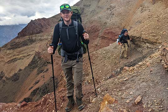 Two backpackers traverse steep and rocky slopes on a guided backpacking trip