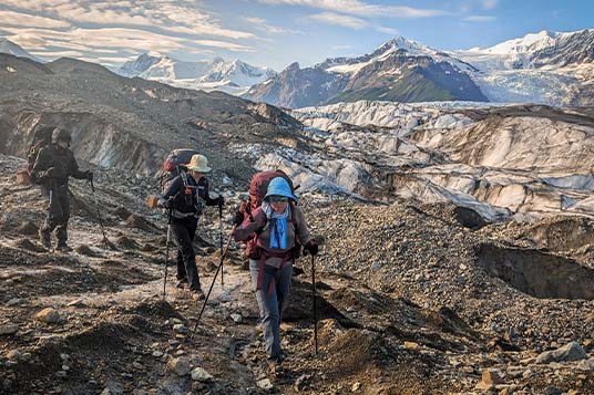 Two backpackers make their way down glacial moraine