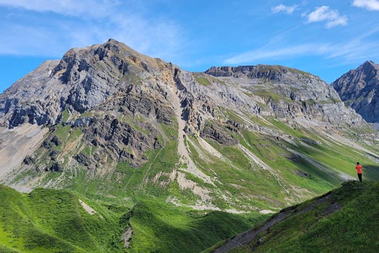 A small hiker dwarfed by the enormous Wrangell Mountains