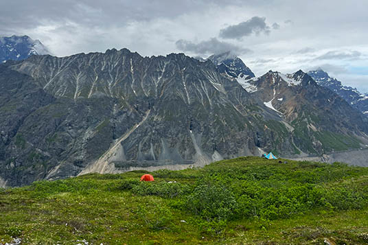 A red tent set up in front of a backdrop of beautiful Wrangell Mountains
