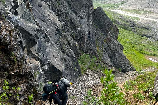 A backpacker moves up a narrow, rocky gully