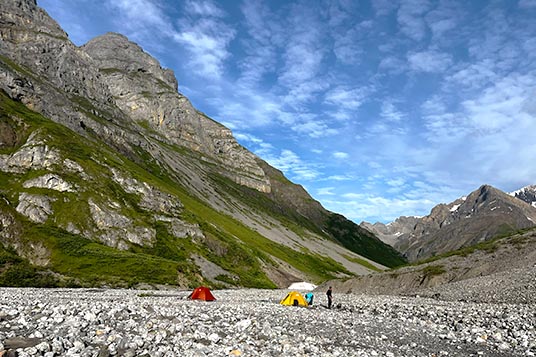 A backcountry camp set up on rocks at the base of a mountain