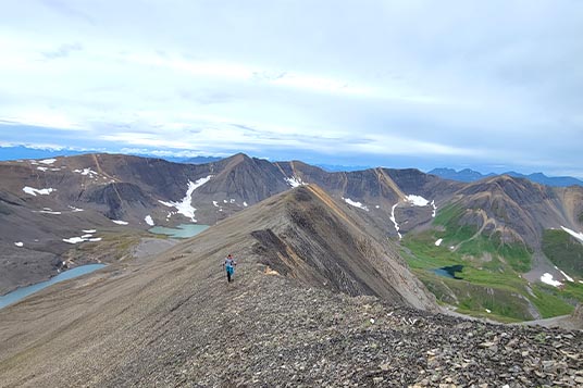 A tiny hiker on the shoulder of a rocky mountain