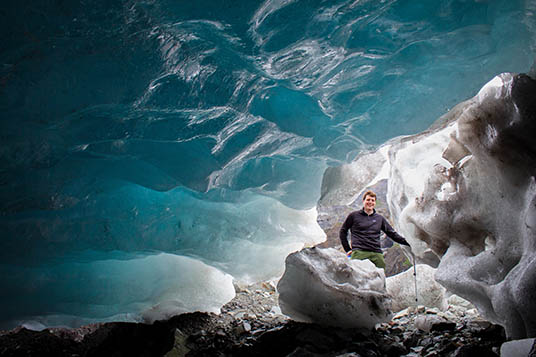 A man explores blue glacial ice in Alaska