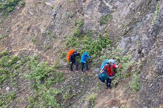 Alaskan backpackers follow their guide through exposed terrain