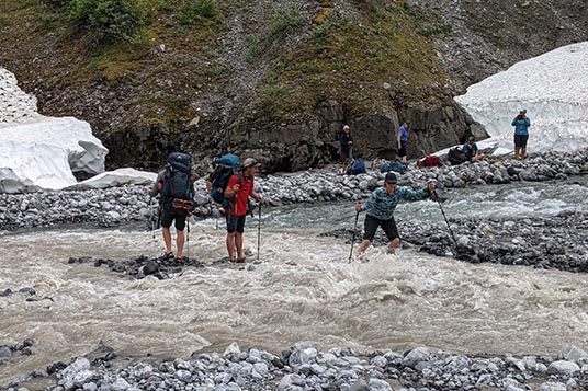 A group of backpackers navigate a creek crossing