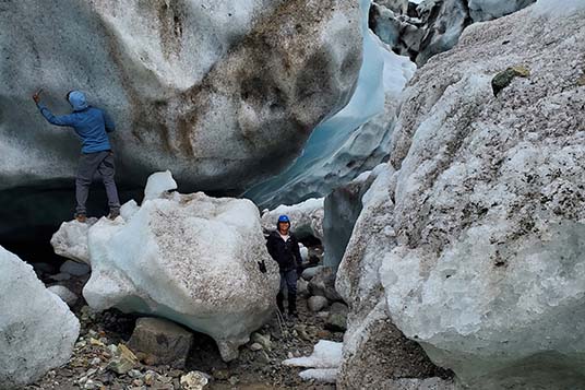A woman poses next to glacial ice