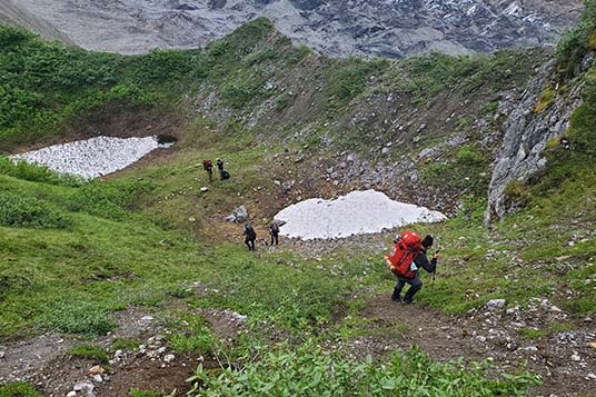 Backpackers descend a steep slope